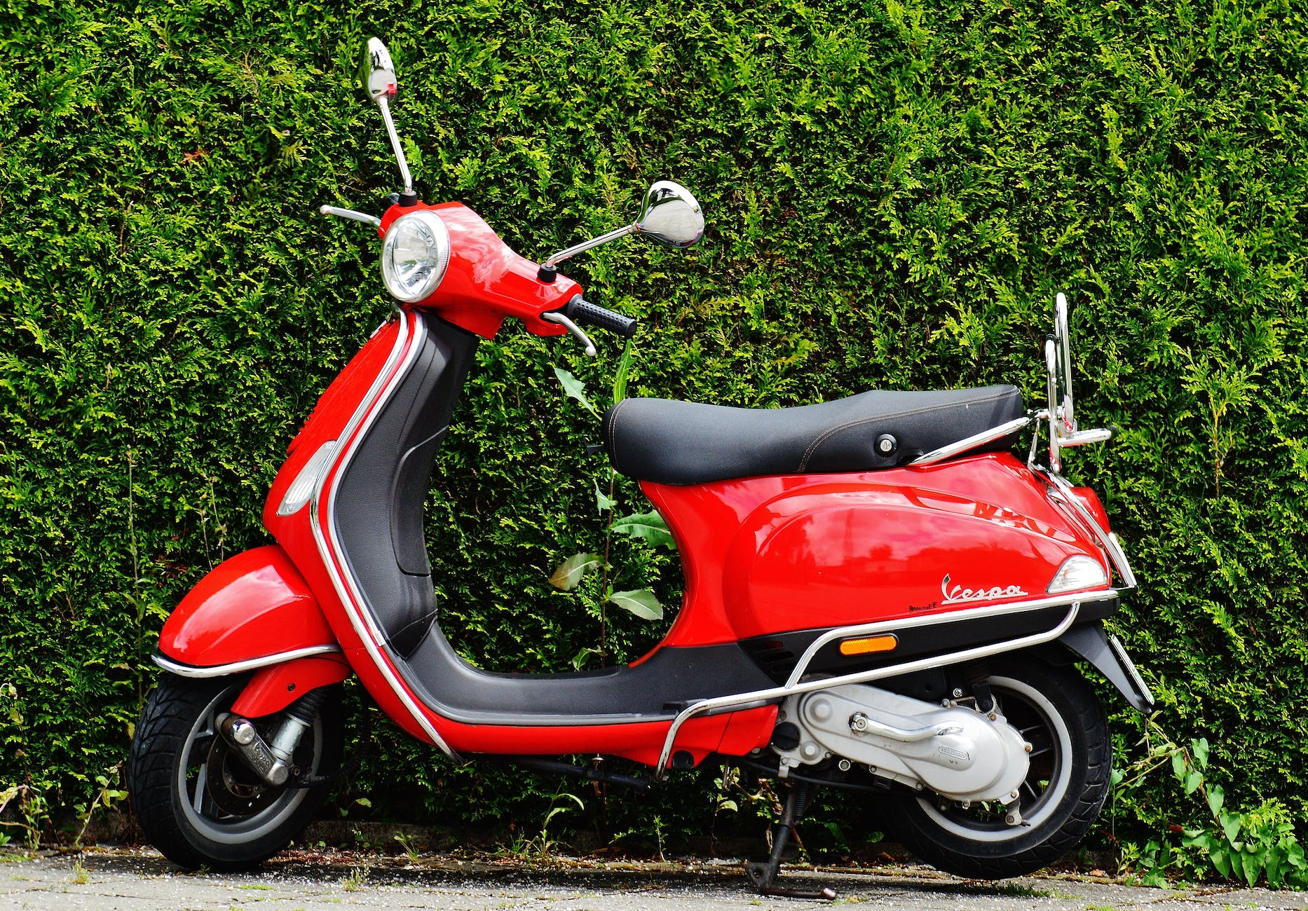 red and black moped scooter beside green grass